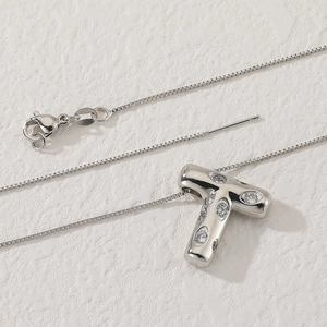 Macro shot of silver letter T pendant with zircon inlays and fine box chain