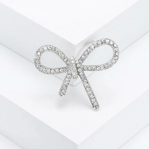Elegant silver bow brooch with crystal rhinestones on a clean geometric white background