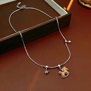 Collier minimaliste en argent avec pendentif cheval en bois et clochette sur fond sombre