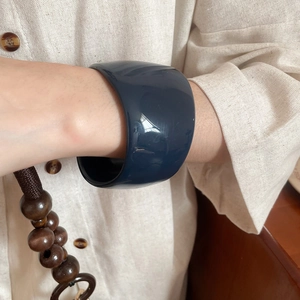 Close-up of a minimalist chunky dark blue resin bangle with a glossy polished finish