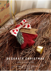 Close-up of plush red Christmas tree hanging ornament with golden bell and pine needle