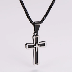 Detail shot of a black and silver double-layered cross pendant on a woven chain necklace