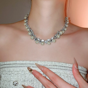 Close-up of elegant pearl necklace with diamond rhombus pendant on female neck