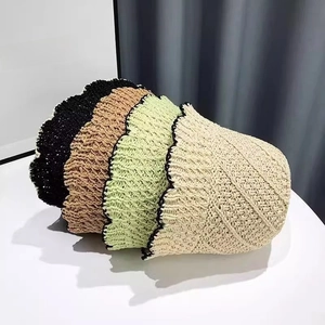Detail view of colorful hand-knitted straw bucket hats with wavy brim and breathable texture