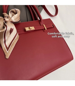 Détail du sac à main rouge en cuir grainé avec fermoir doré et foulard en soie à motifs