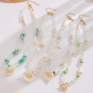 Beach style necklace set with natural shells, starfish charms and beads on beige background