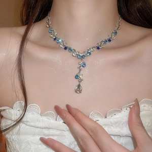 Detail of floral necklace with blue and clear teardrop crystals on model neck