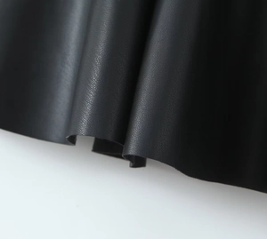 Primer plano de la textura de cuero sintético granulado negro en el vestido corto
