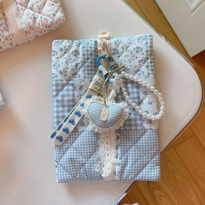 Detail of blue floral quilted fabric bag with pearl chain and lace heart pendant