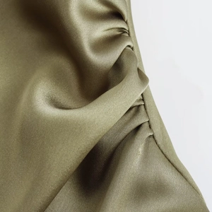Detailed close-up of olive green satin dress featuring elegant pleated texture and silk sheen