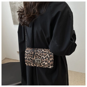 Detail of leopard print crossbody bag with chain strap and metal clasp on model