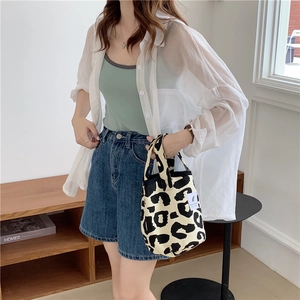 Close-up of leopard print canvas tote bag styled with denim shorts and casual summer wear