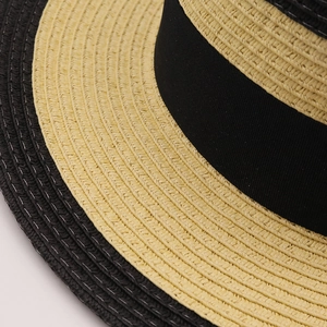 Gros plan sur le chapeau de paille bicolore montrant le tressage fin et le ruban en satin noir