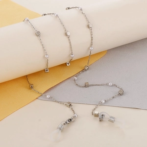 Silver chain with white faux pearls and square beads on white cylindrical props
