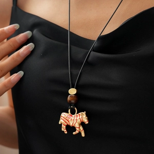 Close-up of golden zebra pendant with red stripes on black ethnic leather necklace