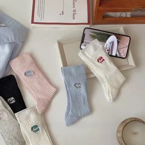 Detail of multi-color ribbed socks with 'FUN TIME' embroidery on casual cotton fabric