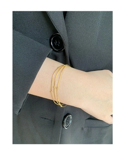 Makroaufnahme minimalistischer goldener dreilagiger Kugel-Schlangenarmband am schwarzen Anzug