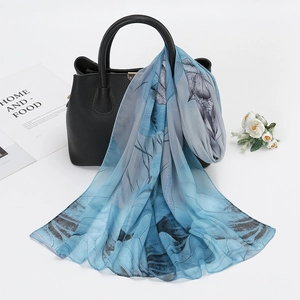 Lightweight floral chiffon scarf in blue and gray draped over a black textured handbag