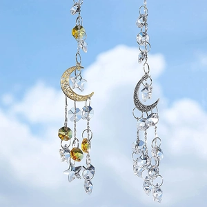 Hanging gold and silver moon star suncatchers with crystal prisms against blue sky