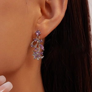 Close-up of silver-plated leaf drop earrings with purple zircon floral clusters