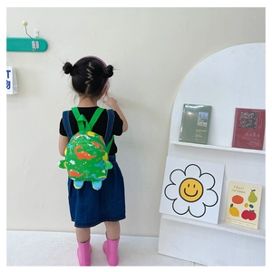 Detail view of a green toddler backpack with colorful cartoon dinosaur prints for school