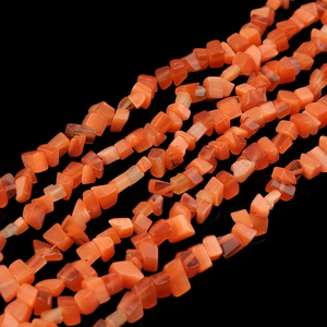 Nahaufnahme von orangefarbenen Karneol Kristall Splitterperlen fur die Schmuckherstellung.