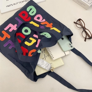 Detail of canvas tote bag with colorful towel embroidered letters and storage items