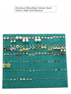 Macro view of assorted jewelry display showing earrings on dark green microfiber velvet board