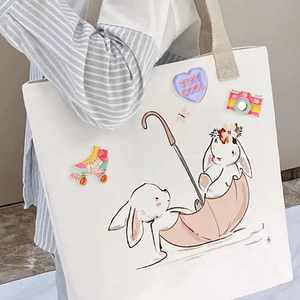 Détail des broches en émail avec cœur violet, appareil photo et patins sur sac en toile