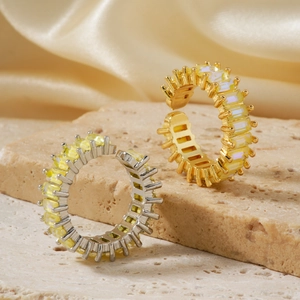 Detail view of gold and silver rings with yellow gemstones on a beige stone and silk cloth