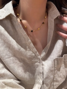 Détail du collier plaqué or 18k avec perles oeil de tigre sur un mannequin sous la lumière