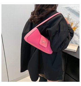 Pink baguette shoulder bag with metal bow detail shown on a model wearing a black blazer