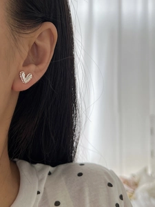 Close-up of heart-shaped silver earrings with elegant ripple texture on a model's ear