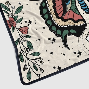 Detailed view of flannel blanket featuring artistic butterfly and floral tattoo style prints
