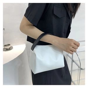 Minimalist white tote bag with black wide handle shown on a model for scale and style