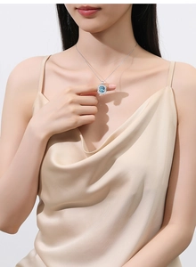 Detailed close-up of a blue rectangular cut gemstone pendant with diamond halo on silver chain
