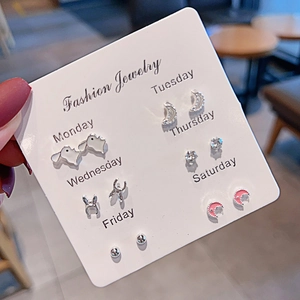 Detail of 6-pair weekly stud earring set on display card held by hand