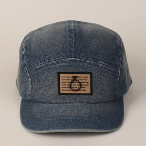 Detail van de vintage denim pet met decoratieve patch en een kleine zwarte metalen ring