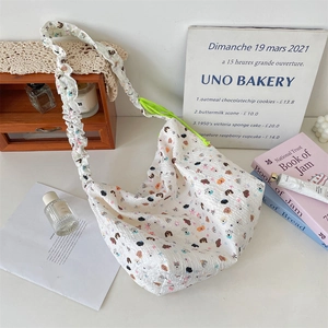 Détail du sac bandoulière en seersucker blanc avec motifs de dessins animés et cordon vert