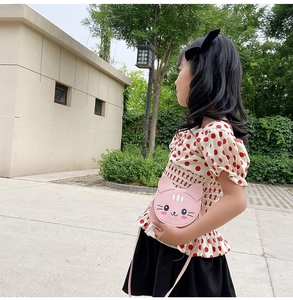 Pink cartoon cat-shaped kids crossbody bag made of PU leather shown on an outdoor model