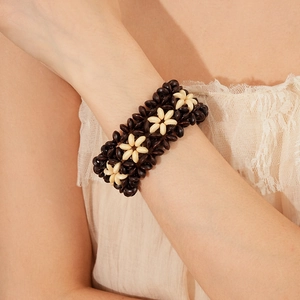 Close-up of Bohemian woven floral bracelet in dark brown and beige on model's wrist