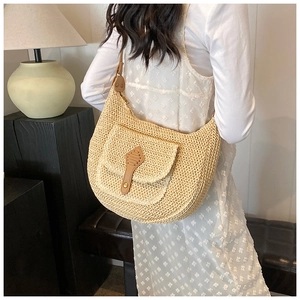 Close-up of woven straw hobo bag with leather strap and decorative buckle detail
