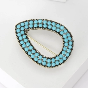 Macro view of Turkish evil eye brooch with blue beads and vintage gold hollow metal