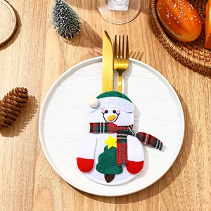 Festive snowman cutlery holder set on a white ceramic plate with Christmas decorations