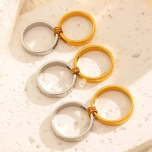 Macro shot of interlocking gold and silver stainless steel rings on a white textured stand