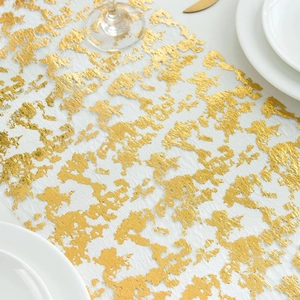 Detailed view of white mesh table runner with gold foil pattern for wedding decor