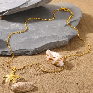 Detailed close-up of a golden starfish pendant on sand with shells and stones