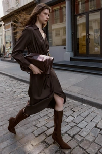 Détail d'une robe midi plissée marron foncé avec col en V et pochette en cuir assortie