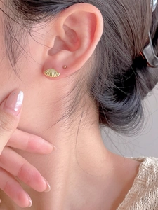 Close-up of golden shell stud earrings on model for a minimalist and elegant look
