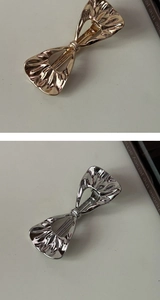 Detail of metallic bow hair clips with irregular pleated texture in gold and silver